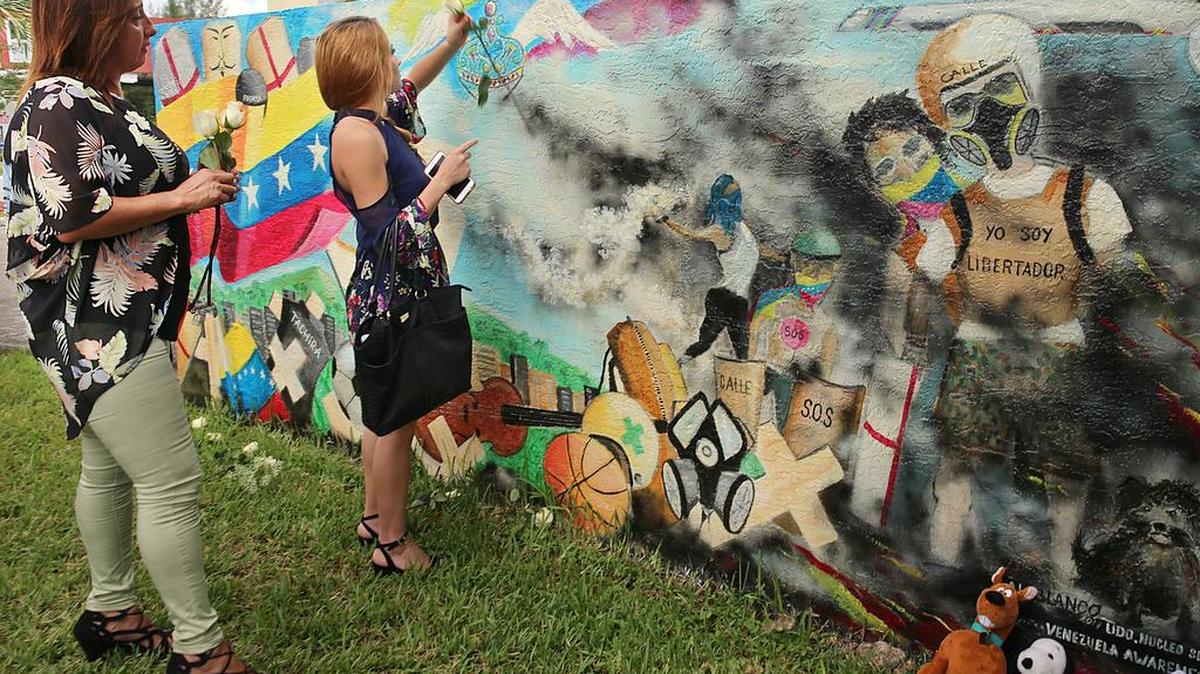 Maria Eugenia Tavares (izq.) y su hija Alejandra Carmona colocan flores en el mural homenaje a los caídos en las protestas antigubernamentales en Venezuela.