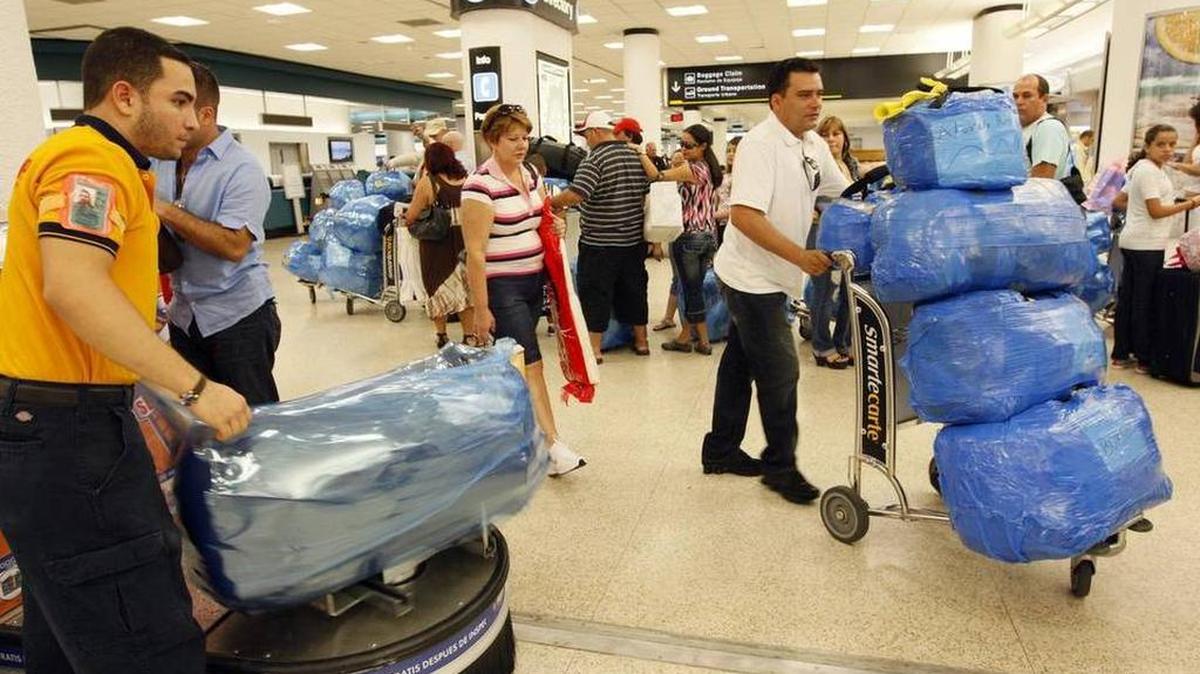 Un empleado de Safe Wrap envuelve el equipaje de un pasajero que vuela a Cuba en el Aeropuerto Internacional de Miami.