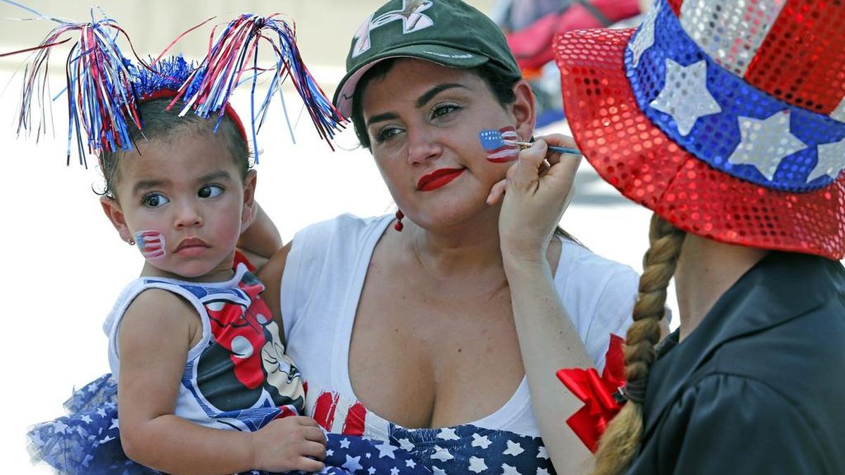 A Marcela Alzate, con su hija Olivia, le pintan una bandera de Estados Unidos en el rostro durante las celebraciones del 4 de julio del 2016 en North Beach.