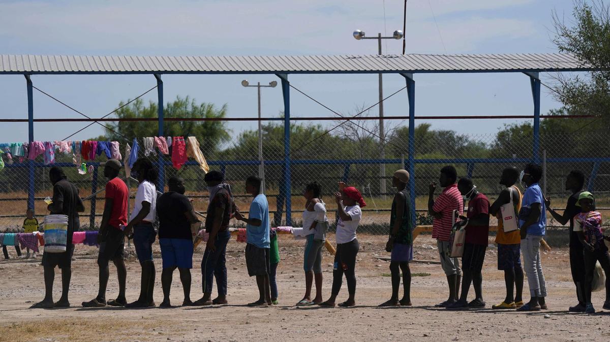 Migrantes, muchos de ellos provenientes de Haití, hacen fila para recibir alimentos en un campamento de refugiados improvisado en un parque deportivo en Ciudad Acuña, México, el miércoles 22 de septiembre de 2021.