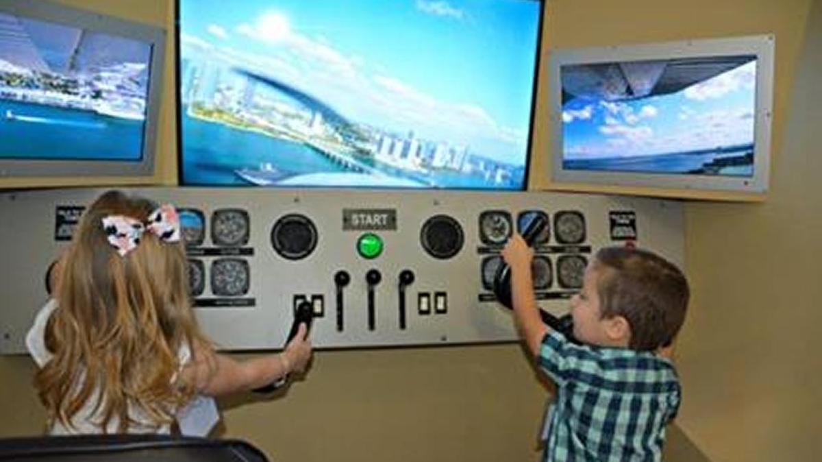 Dos niños juegan con los simuladores de controles de un avión en Plane Fun, en el Aeropuerto Internacional de Miami.