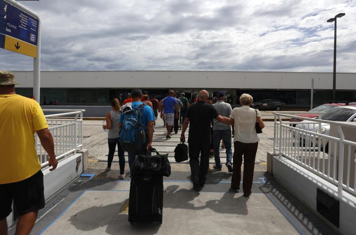 Pasajeros intentan obtener un vuelo el lunes, 25 de septiembre de 2017, en el Aeropuerto Internacional Luis Muñoz Marín en Carolina, Puerto Rico. Puertorriqueños llegaron a Miami en uno de los primeros vuelos que salieron de la isla tras el paso del huracán María para apaciguar la falta de electricidad, aire acondicionado y comunicaciones, e incluso para tratamientos médicos.