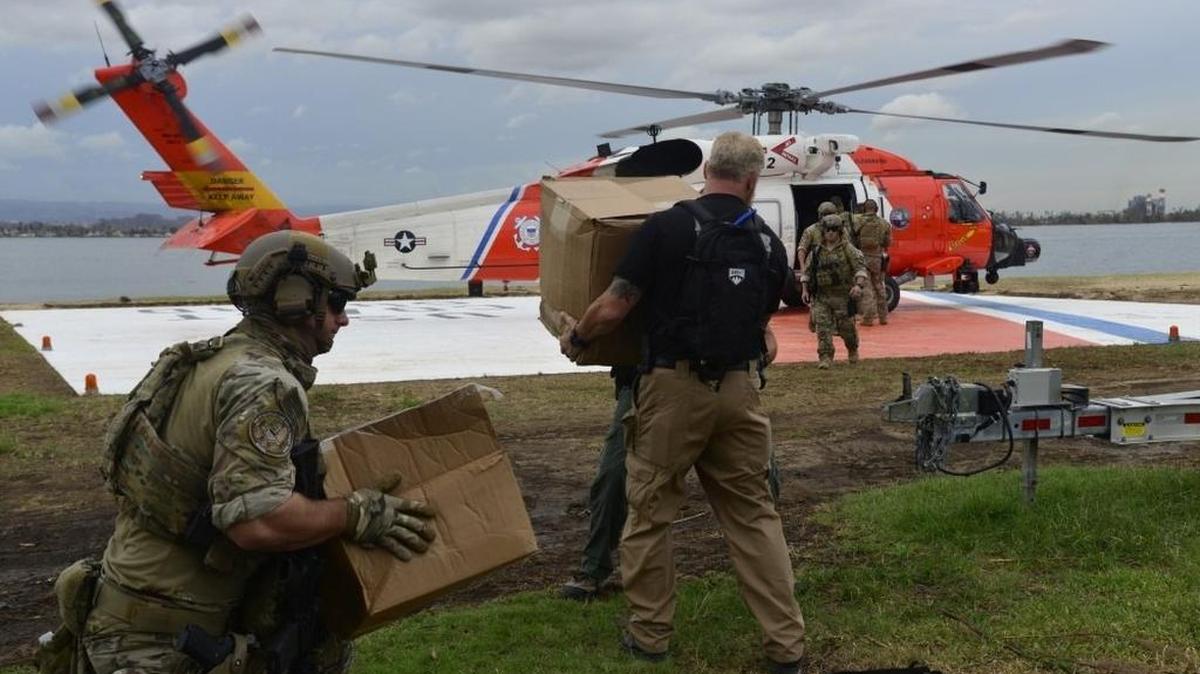 Fotografía cedida por la Guardia Costera de Estados Unidos de agentes del Servicio de Investigación de la Guardia Costera y otros agentes policiales cargan un helicóptero de la Guardia Costera con comida y agua para los residentes el pasado domingo en Utuado, Puerto Rico.