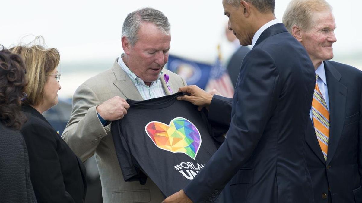 El alcalde de Orlando, Buddy Dyer le muestra una camiseta al presidente de Estados Unidos Barack Obama después de que Obama llegó al Aeropuerto Internacional de Orlando en Orlando, Florida, el 16 de junio de 2016.