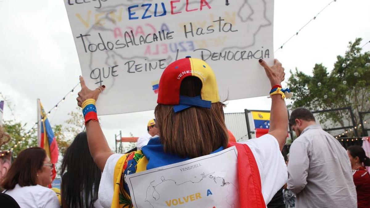 Carol Quintero, sostiene un gran cartel con el lema "Volver a casa”, durante la concentración del miércoles de venezolanos en Doral, quienes se sumaron a la “Toma de Venezuela” que se realizó en Caracas, en respaldo al derecho de decidir si el presidente Nicolás Maduro se mantiene o no en el poder.