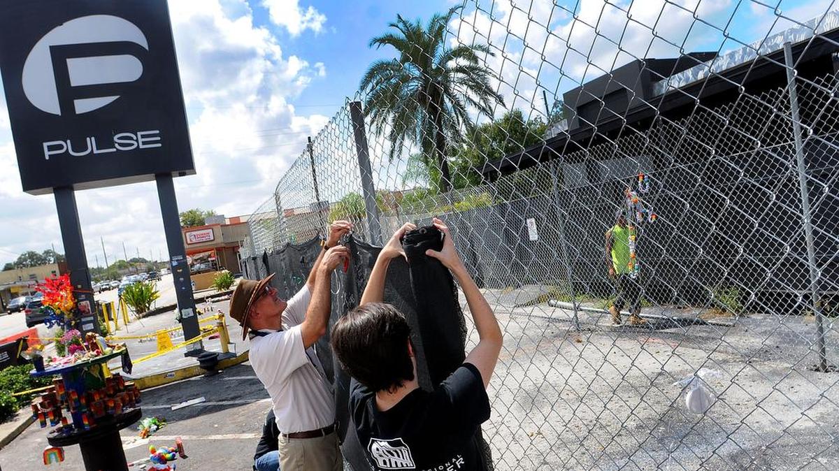 Personal del Centro Regional Histórico del condado Orange retiran este lunes 19 de septiembre 2016, algunos de los artículos dejados sobre la valla del Club gay Pulse en Orlando, Florida (Estados Unidos), donde murieron 49 personas en la peor matanza por arma de fuego ocurrida en Estados Unidos.