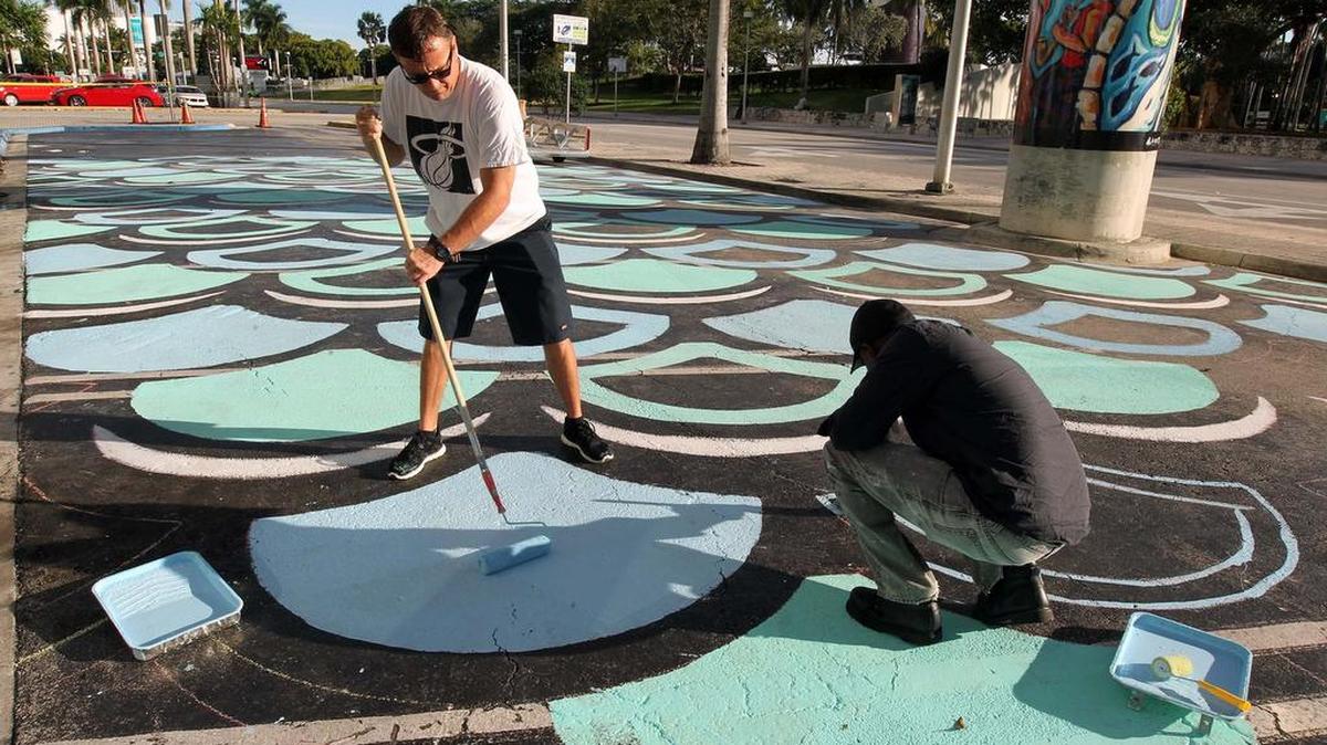 Richard Sargent (izq.) y Sean White pintan diseños sobre el asfalto de Biscayne Boulevard en downtown Miami el jueves.