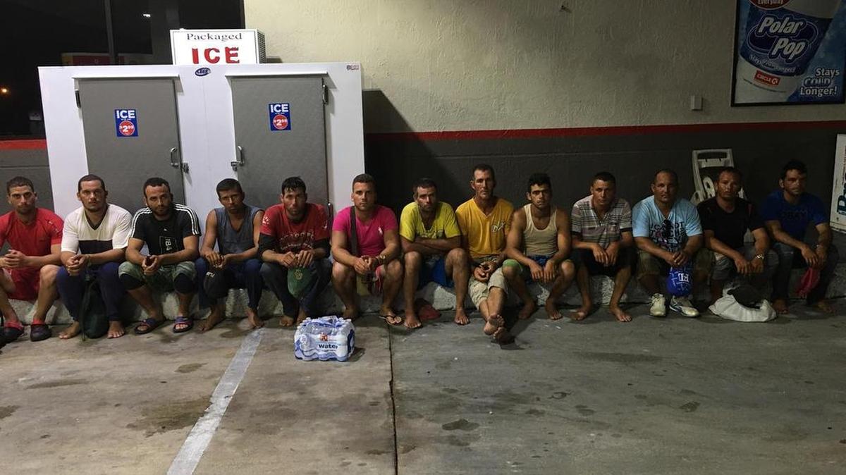 Trece inmigrantes cubanos descansan en una estación de gasolina en Cayo Largo el lunes, después de un viaje de cuatro días desde Cuba.