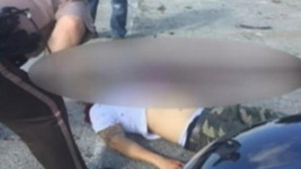 Un oficial de policía asiste a la víctima, tendida en el suelo, en esta foto tomada por uno de los comerciantes de la zona.