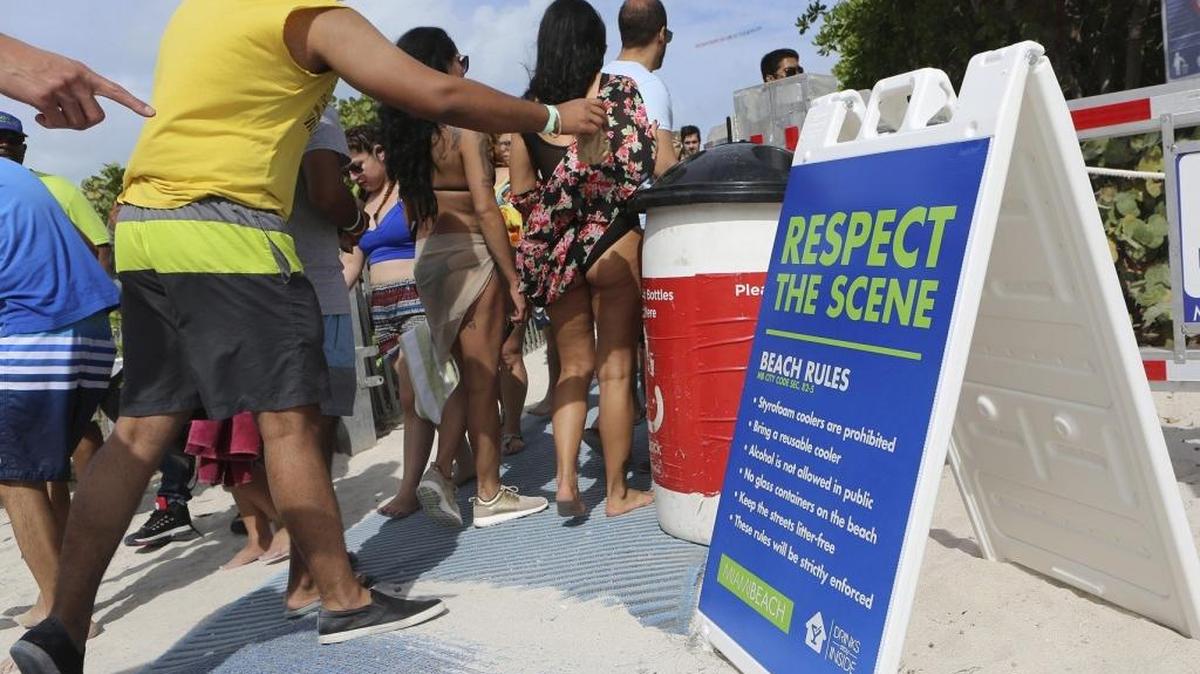 Un joven tira una bolsa dentro de un bote de basura antes de ir hacia la playa, el sábado en Miami Beach.