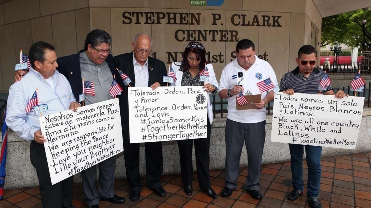 Varios activistas pro derechos de los inmigrantes muestran el miércoles pancartas con lemas sobre la paz y la tolerencia, en inglés y español, frente al edificio del gobierno Stephen Pl Clark en el downtown de Miami.