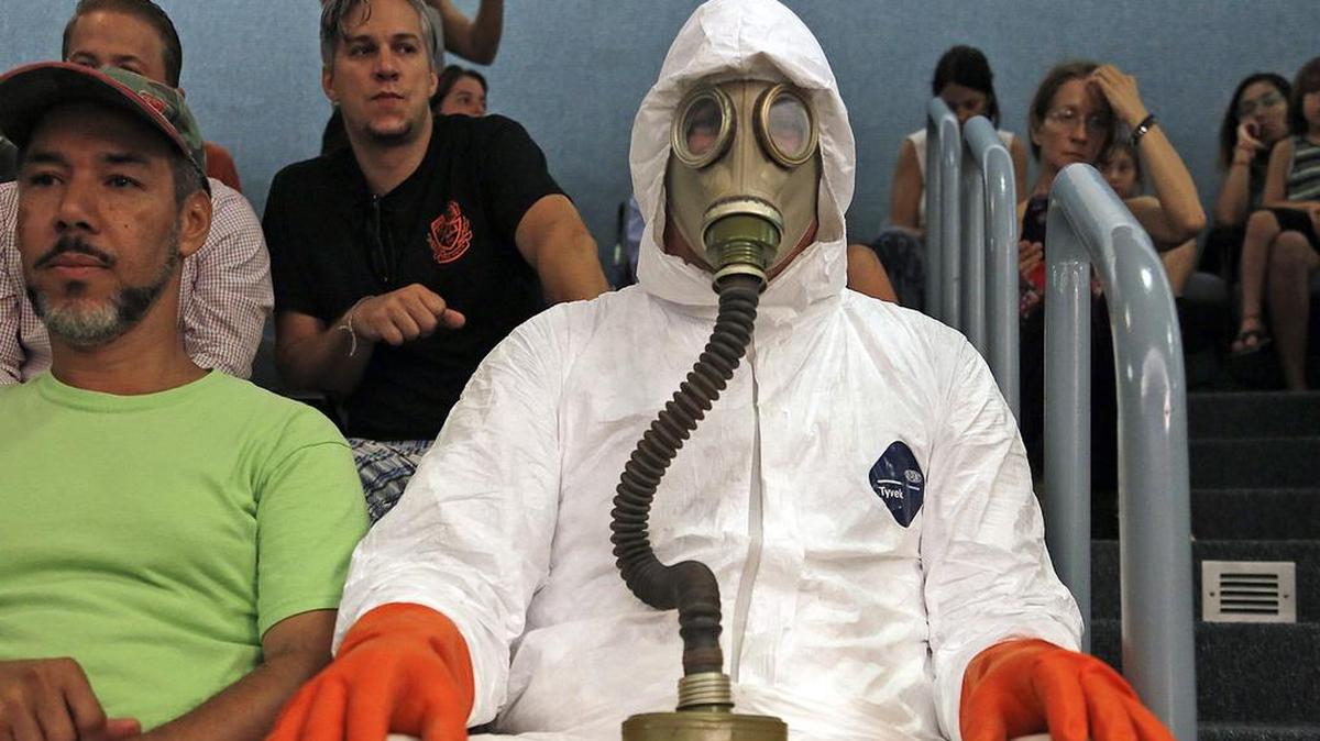 Activista Chris Darsow lleva un traje de residuos peligrosos al taller de emergencia de la comisión de la ciudad de Miami Beach.
