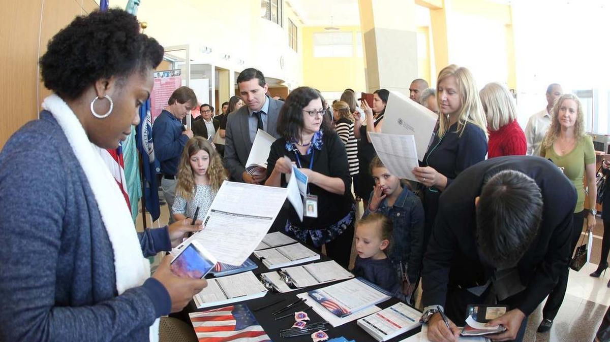 Nuevos ciudadanos de Estados Unidos llenan los formularios de votantes después de la ceremonia de juramentación, en una oficina de la USCIS en Miami, el viernes 12 de febrero.