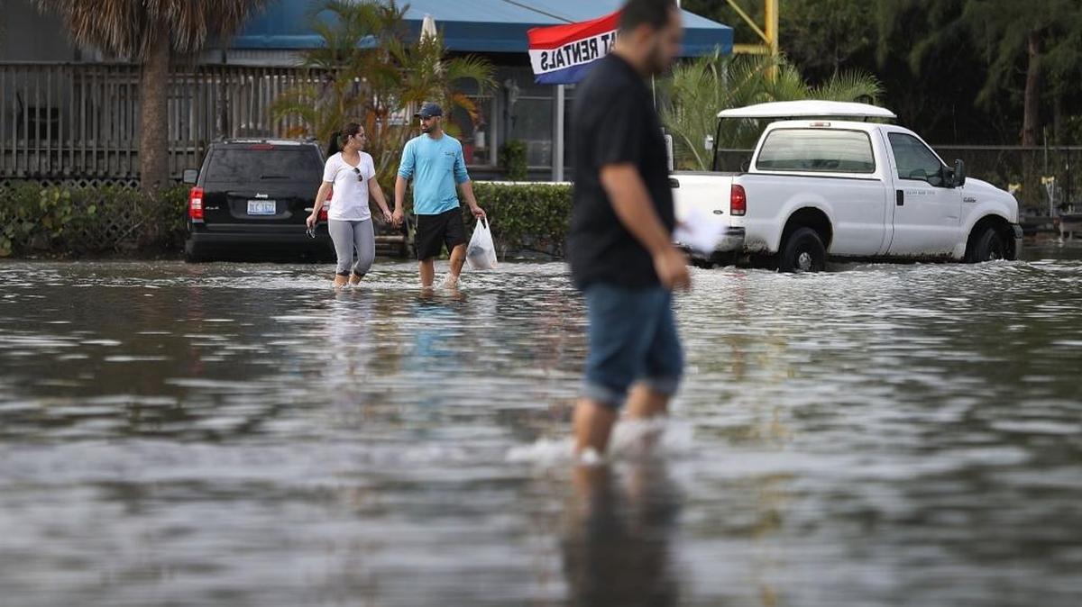 Yaneisy Dueñas (izq.) y Fernando Sanudo caminan el lunes por un estacionamiento inundado del Haulover Marine Center en North Miami.
