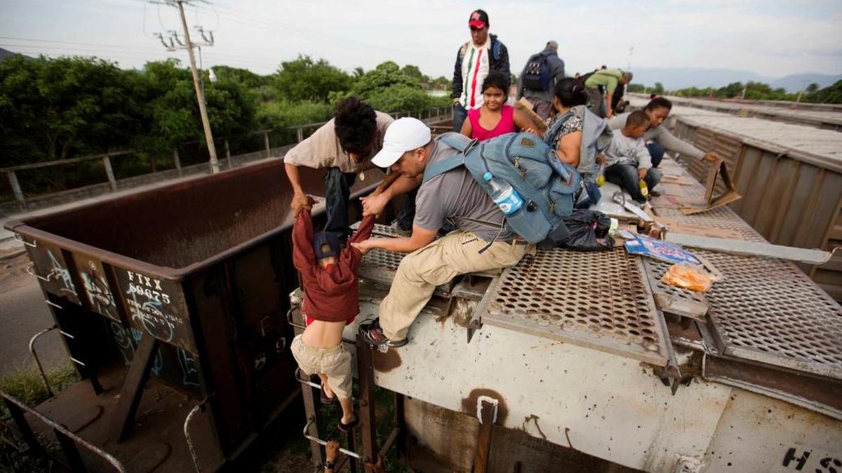 Dos inmigrantes centroamericanos ayudan a un menor a montarse a un tres rumbo norte, en Ixtepec, México, en esta foto del 12 de julio del 2014.