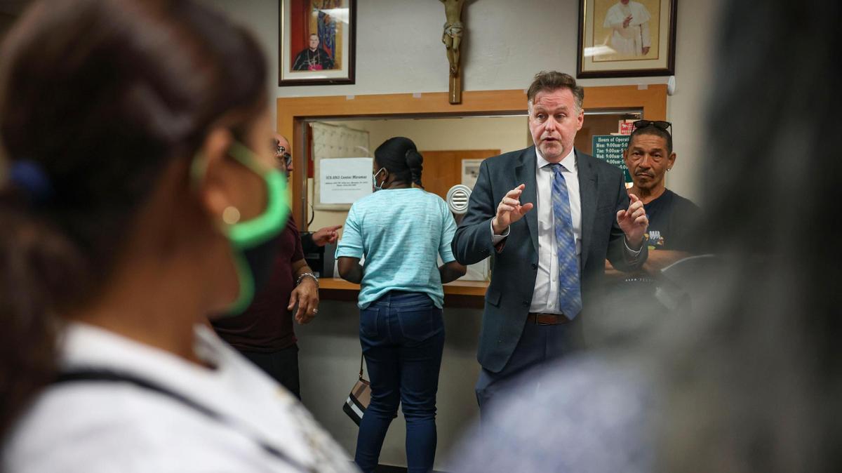 Randy McGrorty, cofundador de Catholic Legal Services, intenta organizar a 40 personas, muchos de ellos inmigrantes, que esperan en el vestíbulo de las oficinas de Catholic Charities, el lunes 9 de enero de 2023, en el downtown de Miami.