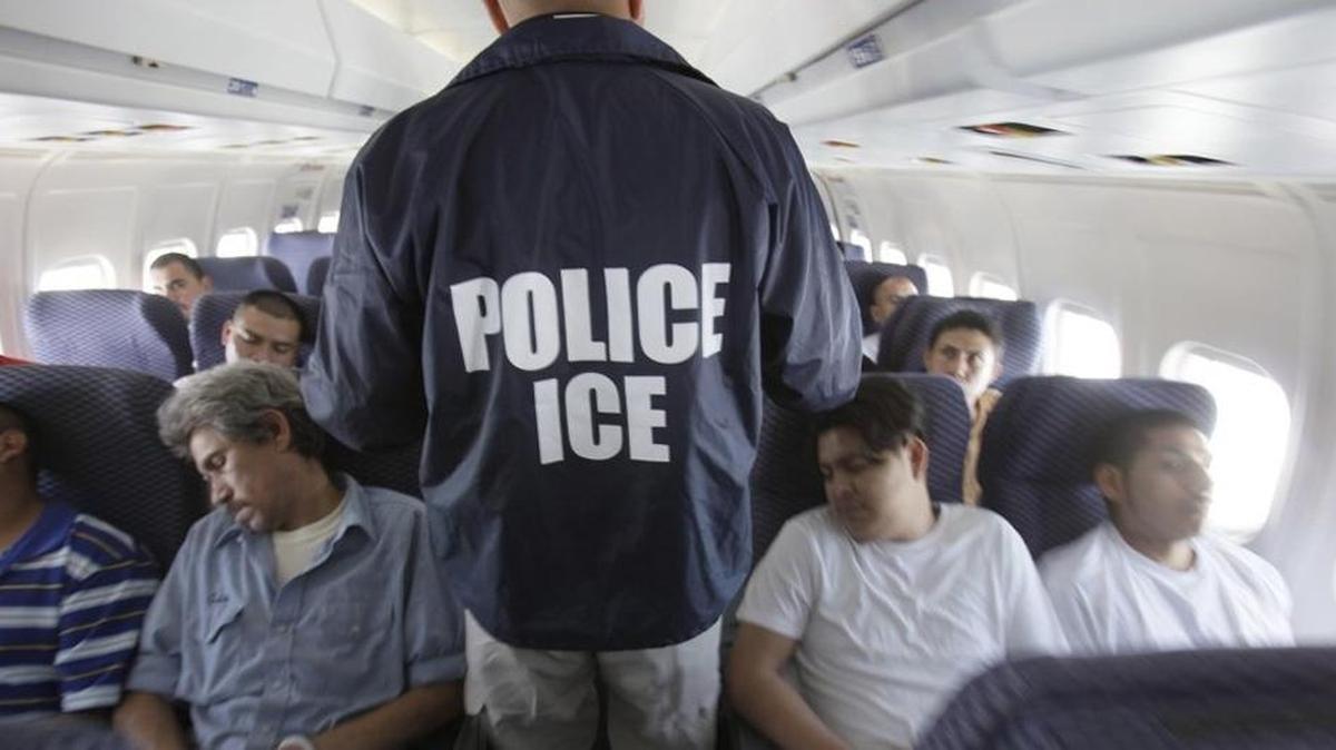 En esta foto de archivo un agente federal camina entre los inmigrantes encadenados que están siendo deportados.