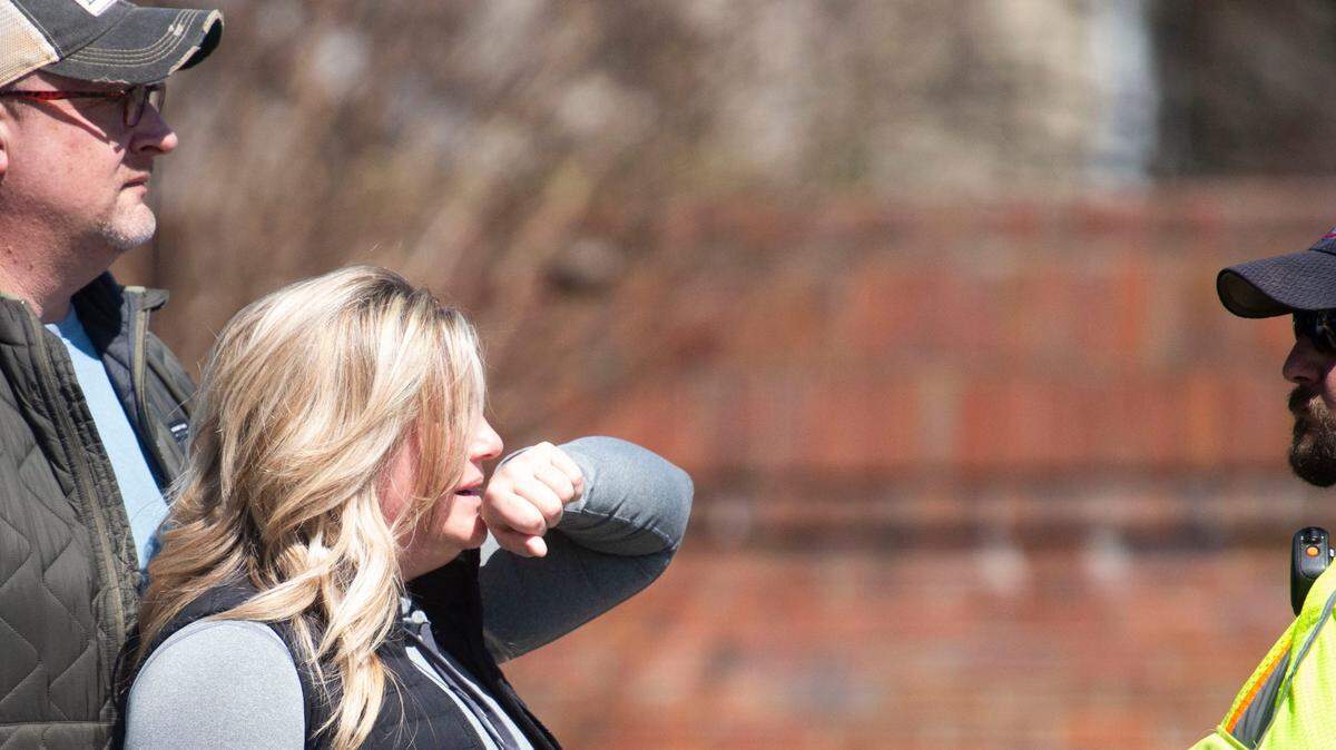 A woman starts to cry as she stands with police near The Covenant School, in Nashville, Tennessee, where six people, including three students, died in a shooting on March 27.