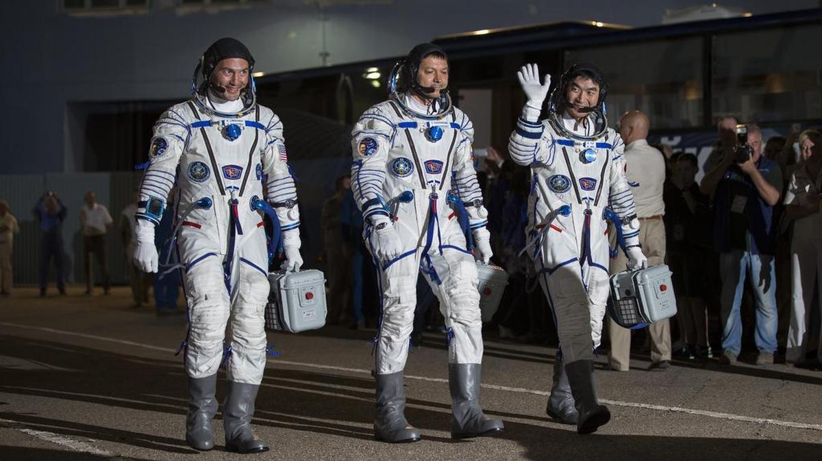 Los integrantes del grupo principal de la expedición 44/45 a la Estación Espacial Internacional (ISS), el astronauta de la NASA Kjell Lindgren (i), el astronauta japonés Kimiya Yui (d) y el cosmonauta ruso Oleg Kononenko (c), saludan antes de abordar el cohete Soyuz TMA-17M el 22 de julio de 2015, antes de su lanzamiento hacia la ISS en Baikonur (Kasajistán).