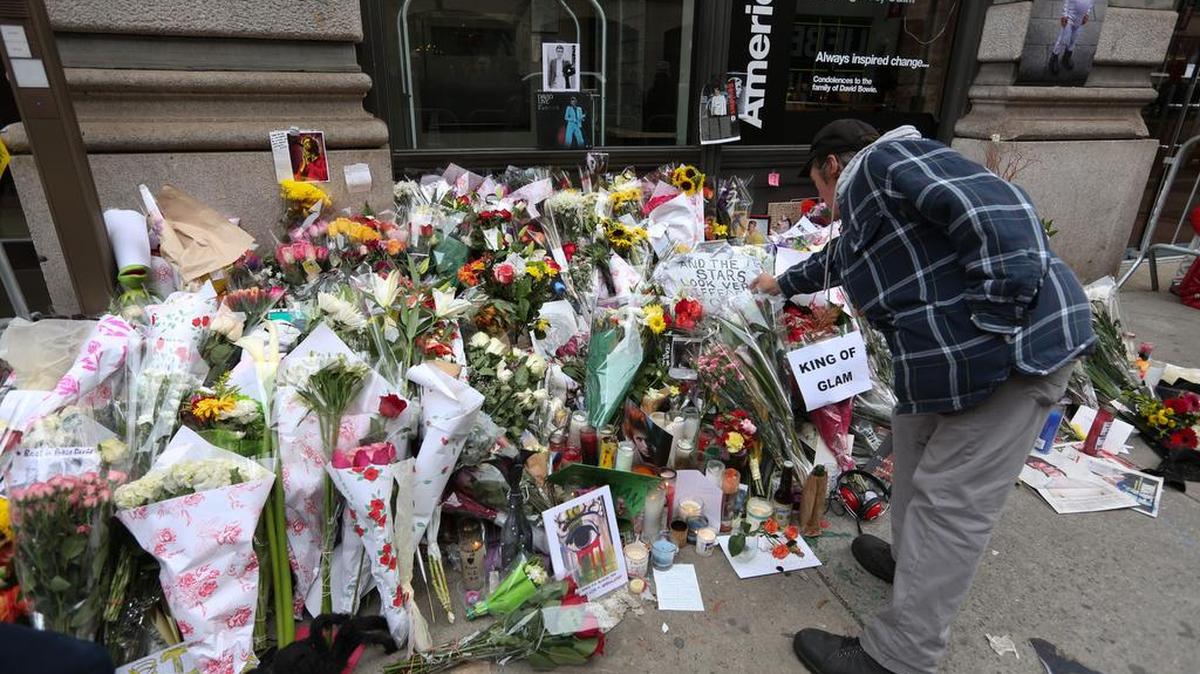 Un hombre deposita flores en las afueras de la residencia en Nueva York de la leyenda del rock.