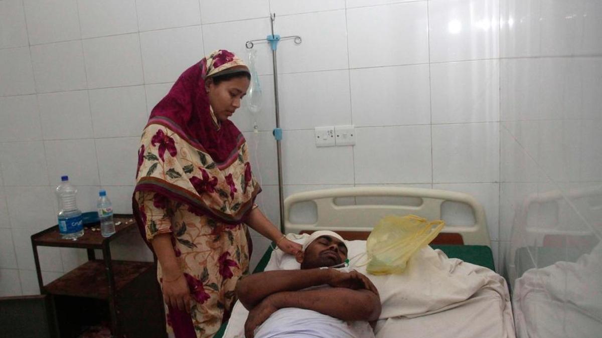 Un trabajador bengalí lesionado es atendido por un pariente mientras se recupera en una sala de un hospital en Gazipur el 3 de julio de 2017, después de resultar herido en una explosión en una fábrica de prendas de vestir.