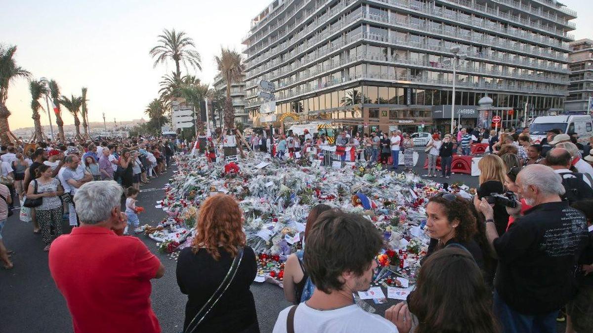 Personas se reúnen alrededor de un monumento improvisado en honor a las víctimas de un ataque terrorista en Niza.
