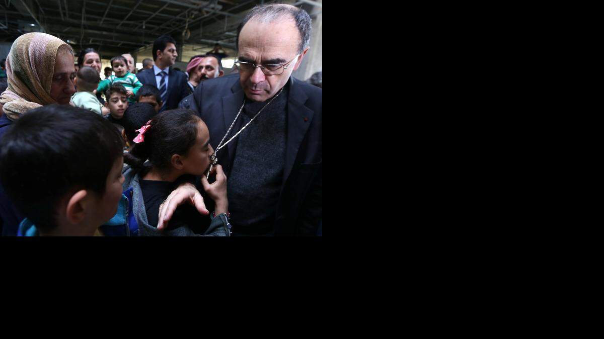<cutline_leadin>Una niña</cutline_leadin> cristiana besa la cruz que lleva el Arzobispo Barbarin en su visita a los cristianos iraquíes, el sábado.