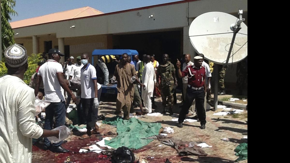
Agentes de seguridad nigerianos y miembros de la Cruz Roja, inspeccionan la zona donde al menos 20 personas murieron el martes al explotar una bomba cerca de una oficina del gobierno local en Zaria, Nigeria. 
