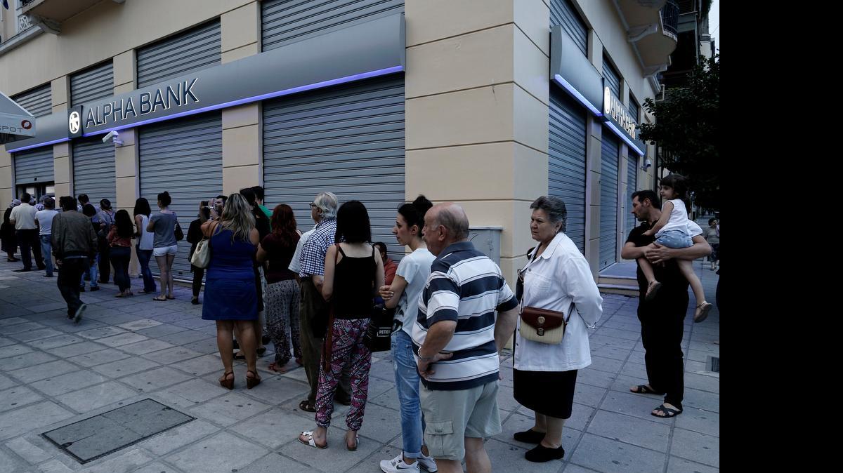
Decenas de clientes hacen fila el domingo para extraer dinero de un cajero automático del Banco Alpha en Tesalónica, Grecia. El gobierno de ese país anunció fuertes medidas de control financiero.

