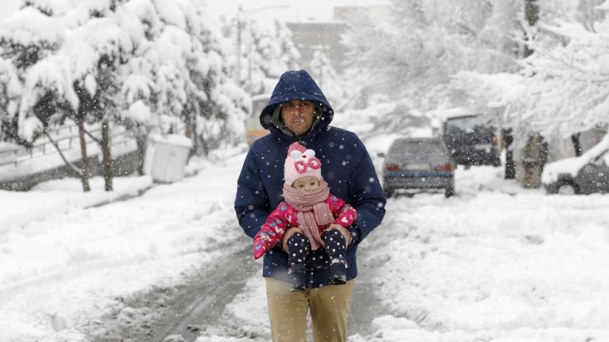 Un hombre camina con su hija por una calle de Teherán cubierta de nieve el domingo 28 de enero.