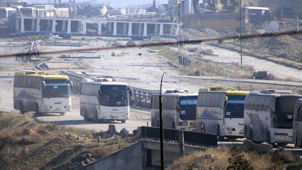 Unos autobuses que transportan combatientes opositores de los distritos sitiados de la mitad oriental de Alepo y a sus familiares salen de los barrios del este de Alepo, Siria, en dirección al área de Al Rashidín, al oeste de la urbe, hoy, 19 de diciembre de 2016.