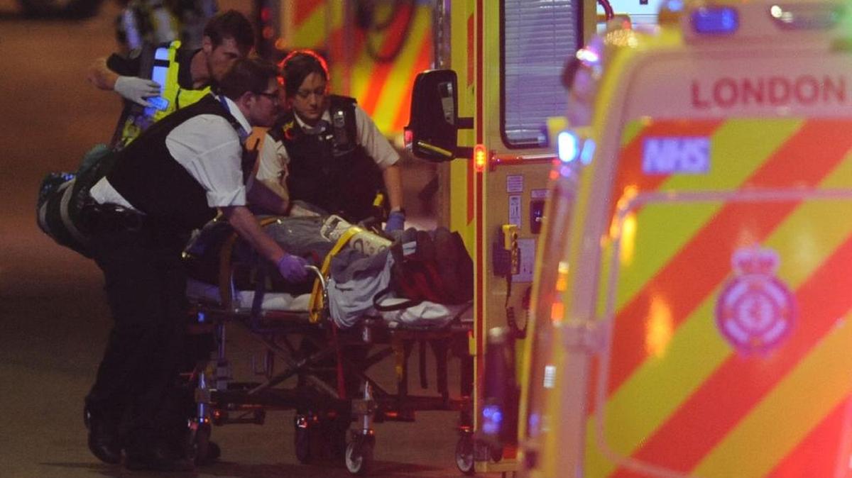 Los agentes de policía y los miembros de los servicios de emergencia atienden a una persona herida en un aparente ataque terrorista en el puente de Londres en el centro de Londres el 3 de junio de 2017.