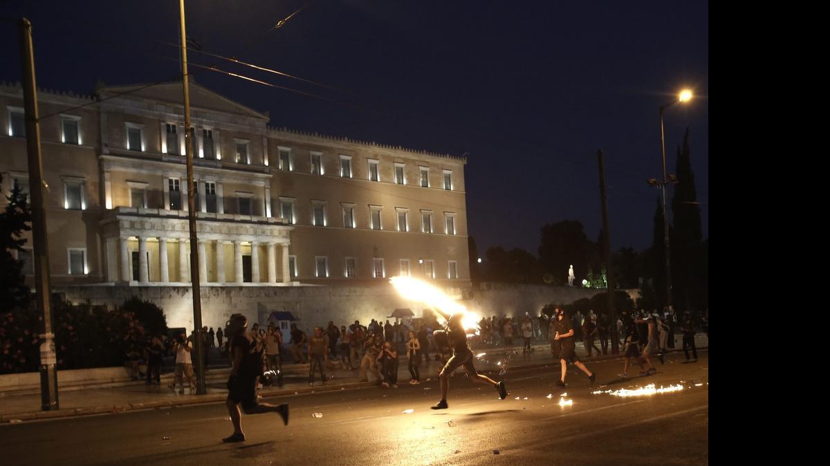 
Manifestantes lanzan cócteles molotov a la Policía, el miércoles, durante las protestas contra el acuerdo alcanzado entre el gobierno y los socios en la céntrica plaza de Syntagma, en Atenas.
