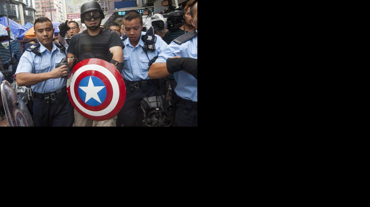 
Policías hongkoneses arrestan a un activista prodemocrático con un escudo del "Capitán América" en Hong Kong (China) hoy, viernes 24 de octubre de 2014. Los líderes del movimiento prodemocracia de Hong Kong han convocado una consulta para el domingo entre los manifestantes para decidir si deben aceptar las propuestas que el Gobierno les presentó el martes para seguir adelante con la negociación sobre una posible reforma electoral.
