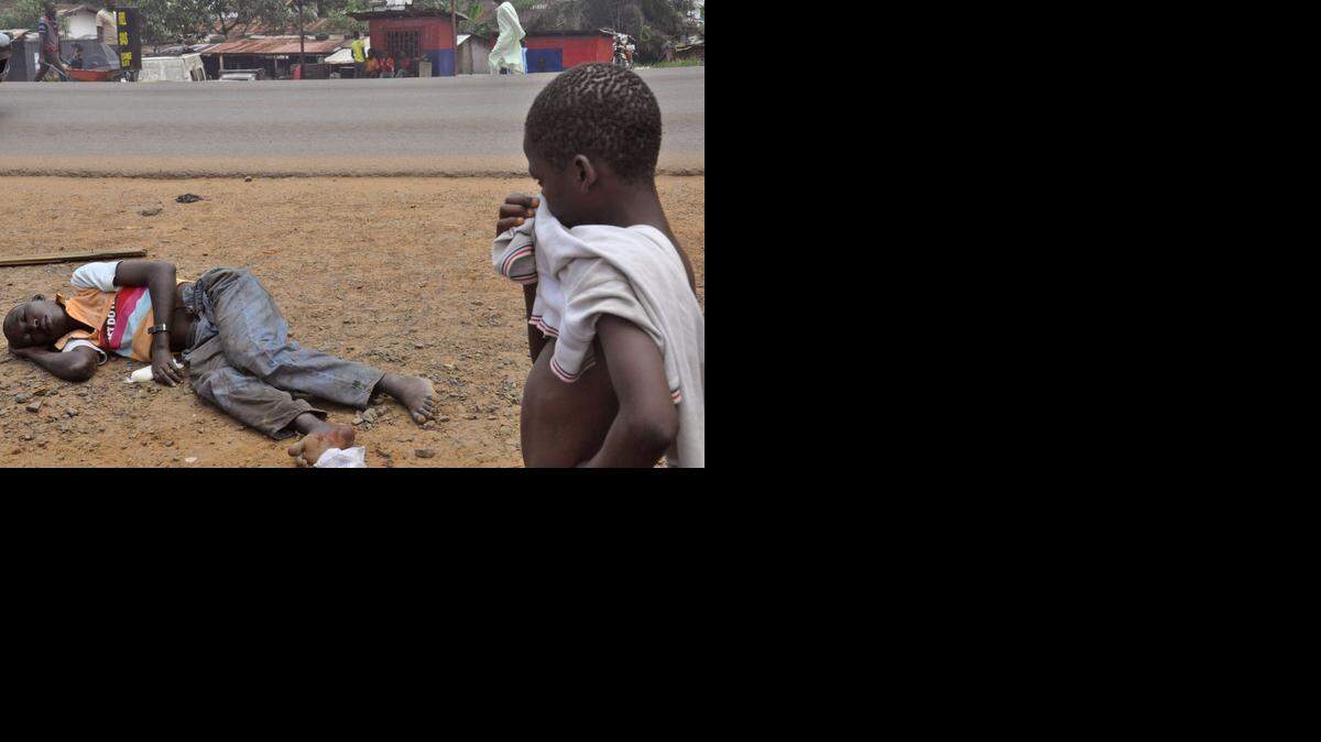 
Un niño mira a un hombre sospechoso de padecer el virus Ebola, en una calle principal de Monrovia, Liberia, el 12 de septiembre de 2014.
