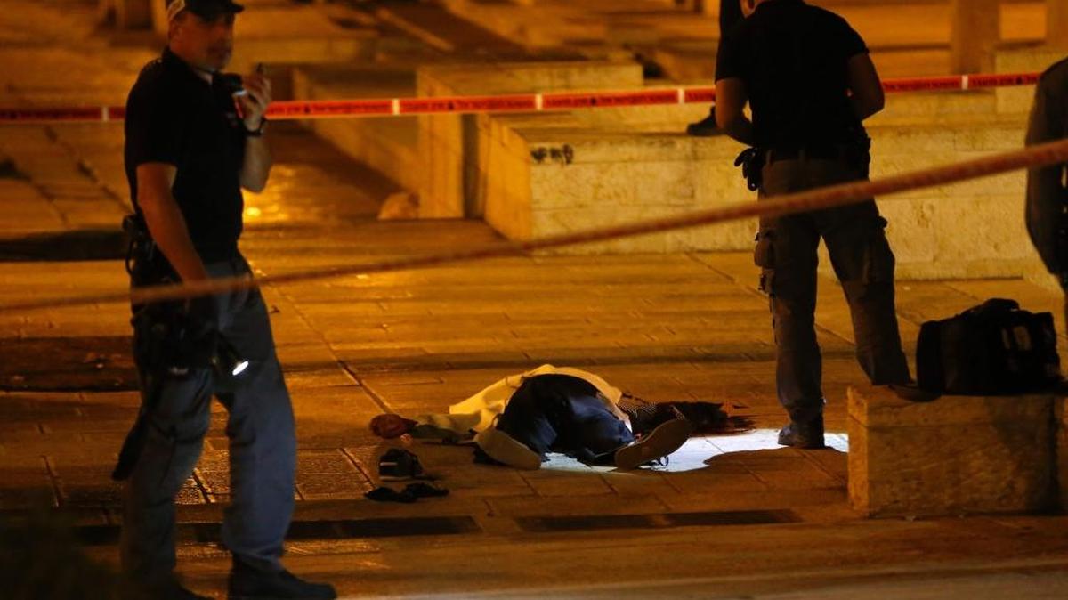 Agentes israelíes junto a una víctima mortal de los ataques el domingo en la entrada a la ciudad de Jerusalén.