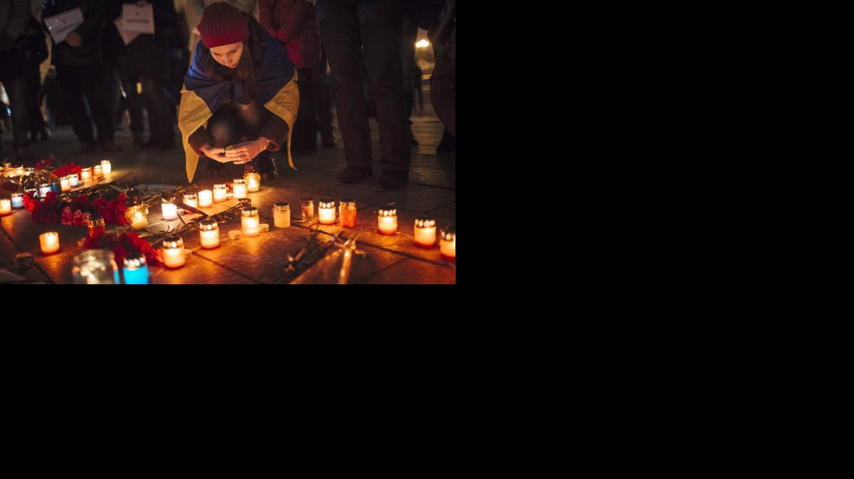 
Una niña arropada con la bandera ucraniana prende velas en una plaza de Kiev, Ucrania, en memoria de las víctimas de la ofensiva lanzada por separatistas prorrusos en Mariupol. 
