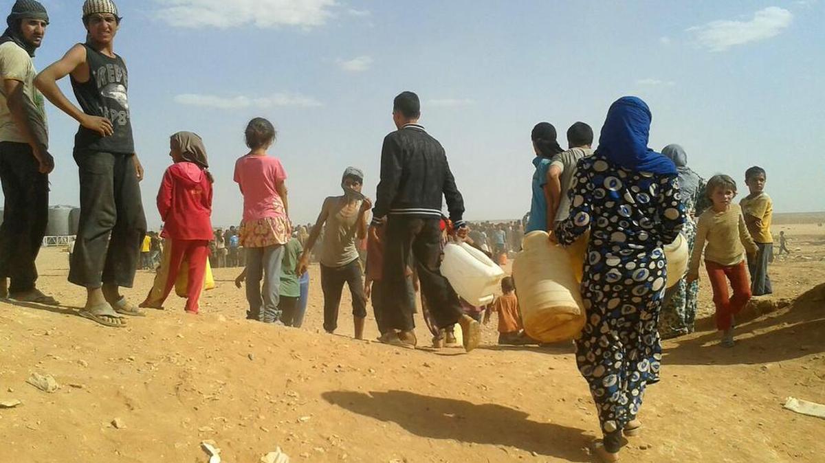 Refugiados sirios en Jordania se reúnen para conseguir agua.