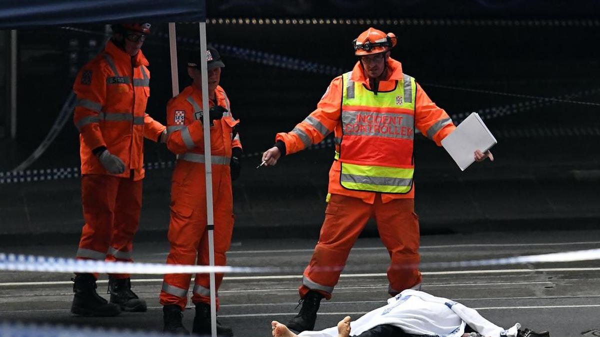 El personal del Servicio de Emergencias del Estado (SES) trabaja en la escena del crimen mientras un cuerpo yace en el suelo tras un ataque con cuchillo en Melbourne el 9 de noviembre de 2018.