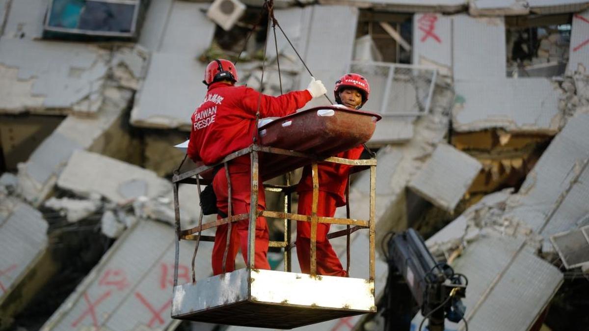 Dos socorristas transportan a una víctima rescatada de un edificio colapsado en Tainan, Taiwán, este domingo.