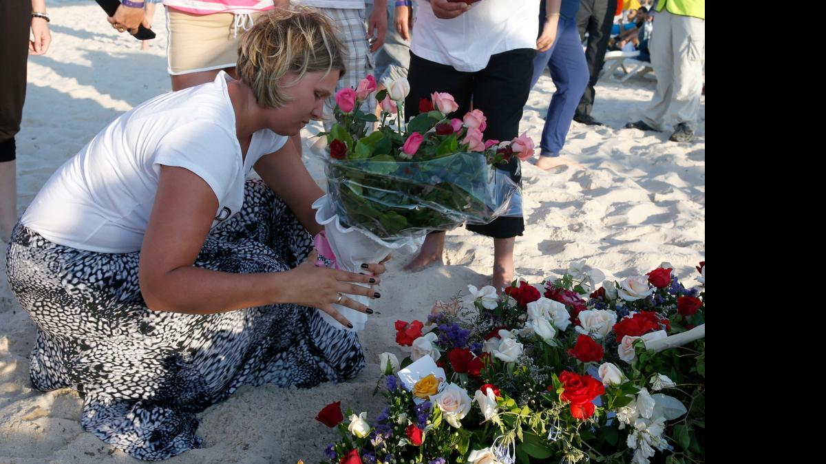 
Una turista pone un ramo de flores en la escena donde varios turistas perdieron la vida tras un ataque de un extremista tunecino.

