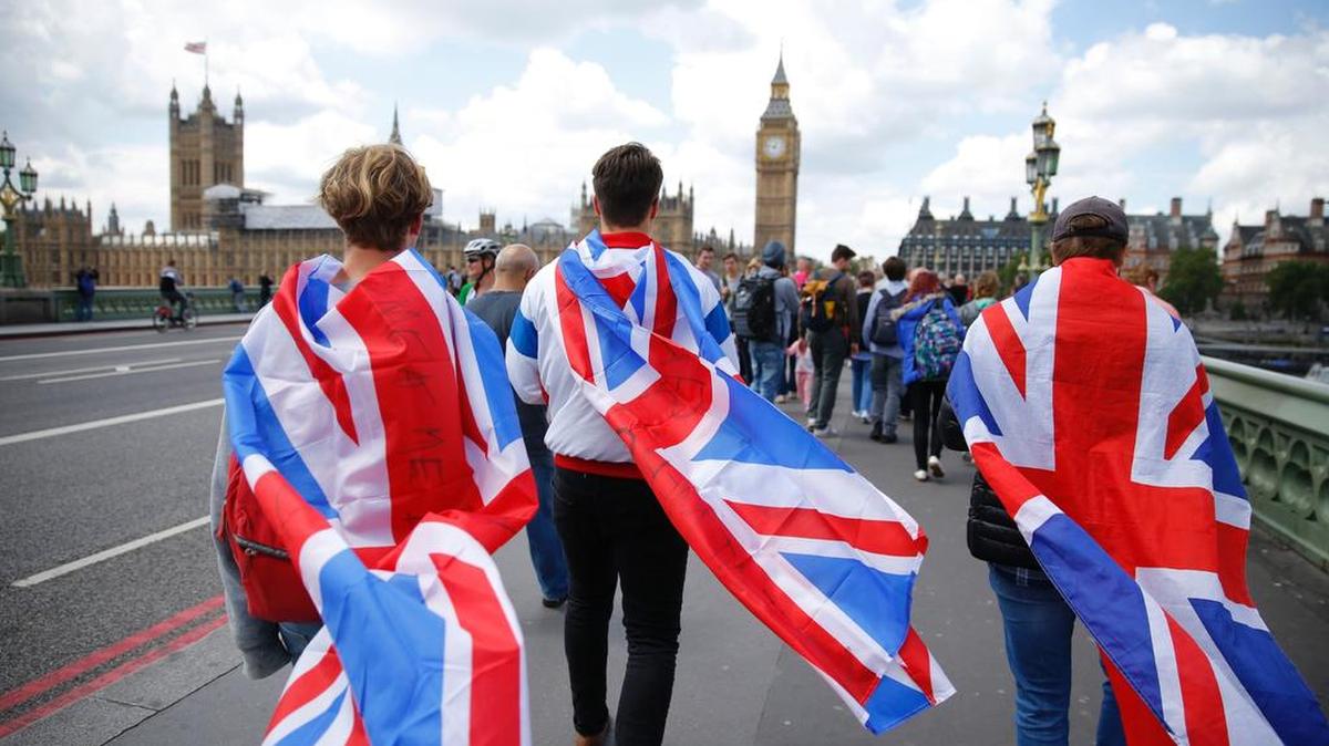 Gente cubierta con la bandera británica camina el puente Westminster el domingo en Londres.