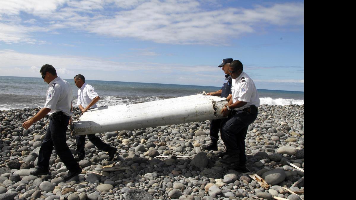 
Agentes policiales transportan los restos de un ala de avión el jueves en la isla Reunion, en el océano Índico. El pedazo de escombro fue transportado a Francia para determinar si perternece al desaparecido vuelo MH370 de Malaysia Airlines.
