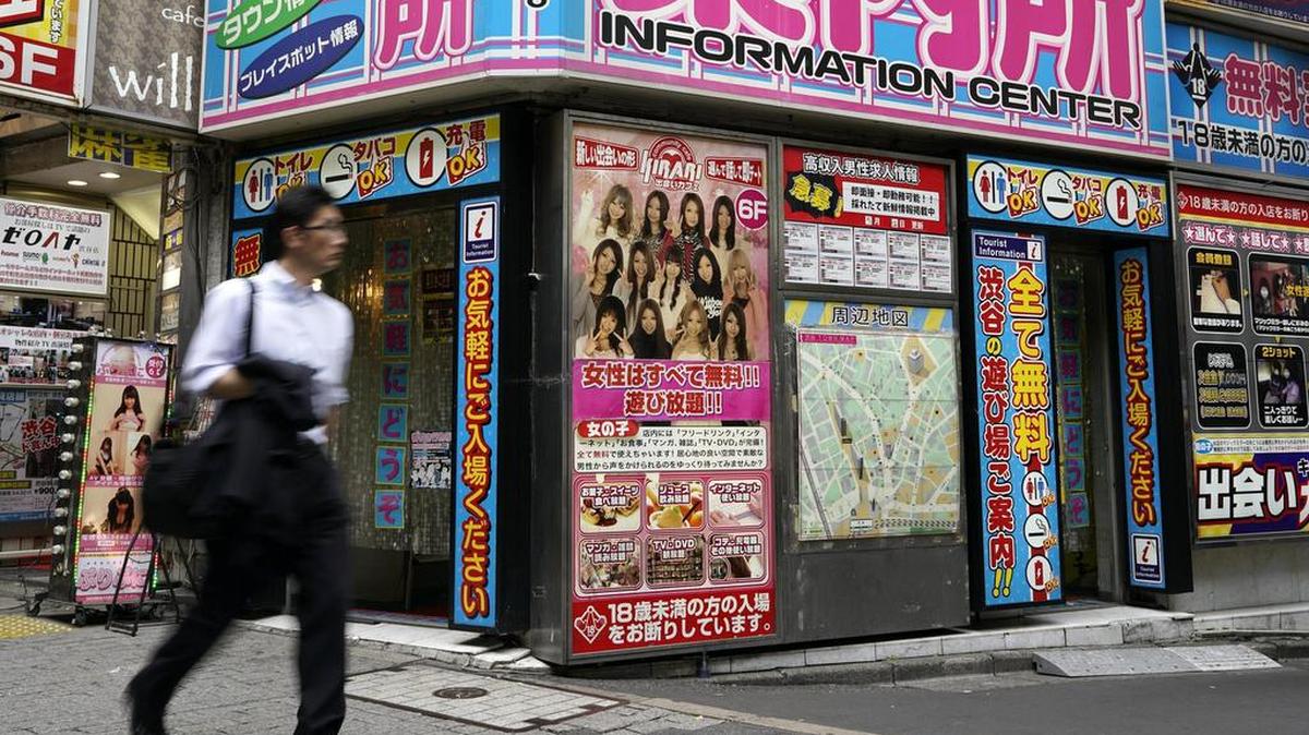 Un hombre pasa junto a un "centro de información" que ofrece asesoría sobre servicios orientados a adultos en el distrito de moda Shibuya en Tokio (Japón) el pasado 24 de mayo de 2017.