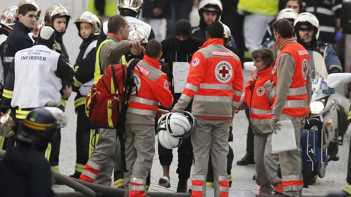 Personal médico asiste a un policía herido durante una operación en Saint Denis cerca de París (Francia) hoy, 18 de noviembre de 2015. La Fiscalía de París confirmó hoy que una mujer se suicidó haciendo estallar su cinturón de explosivos y cinco personas fueron detenidas en Saint-Denis, tres de ellas dentro de un apartamento asaltado por la policía en una operación todavía abierta en relación con los atentados de París del pasado viernes.