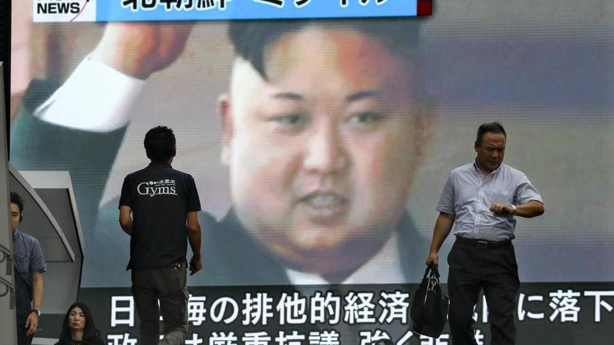Varios viandantes pasan ante una pantalla gigante de televisión que muestra un retrato del líder norcoreano Kim Jong-un mientras se informa del lanzamiento de un misil balístico internacional por parte de Corea del Norte, en Tokio (Japón) el 4 de julio de 2017.