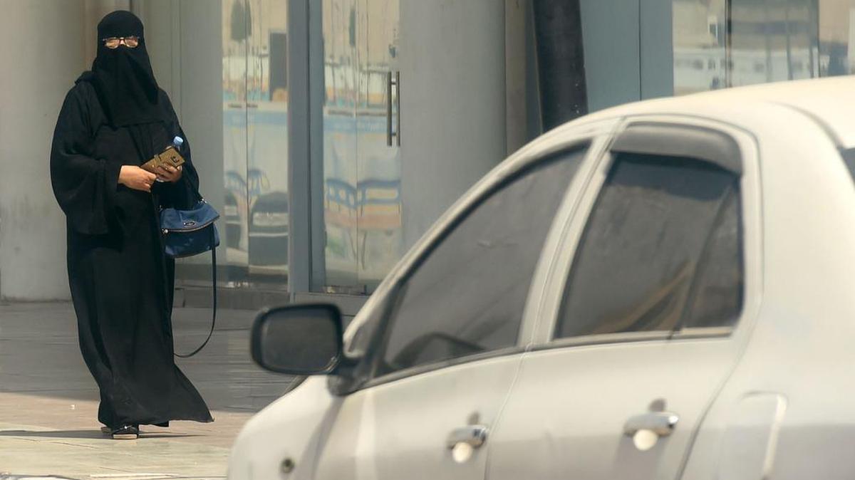 Una mujer camina cerca de coche por una calle en la capital saudita Riyadh el 27 de septiembre de 2017.