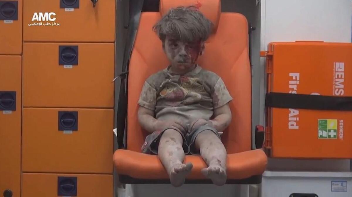 Imagen facilitada por el grupo activista Centro de Información de Alepo (AMC) el 18 de agosto de 2016 que muestra a un niño herido de 5 años, sentado en una ambulancia tras ser rescatado anoche de una vivienda bombardeada en el barrio de Al Qatergui en la ciudad siria de Alepo, ayer.