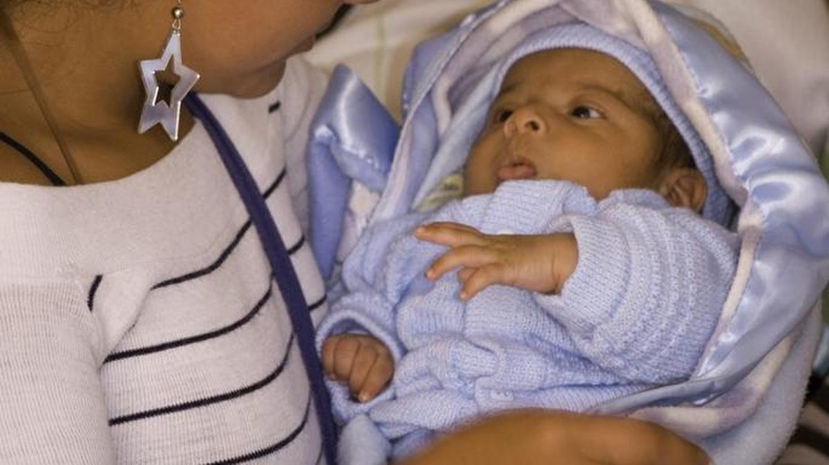 Foto de archivo de una madre adolescente cargando a su hijo de pocos meses de edad.
