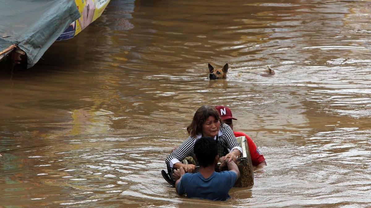 Las autoridades han confirmado que al menos 30 personas fallecieron por la tormenta tropical que azotó Filipinas este viernes. En la foto, una mujer y su mascota intentan salvarse en la ciudad de Cagayan.